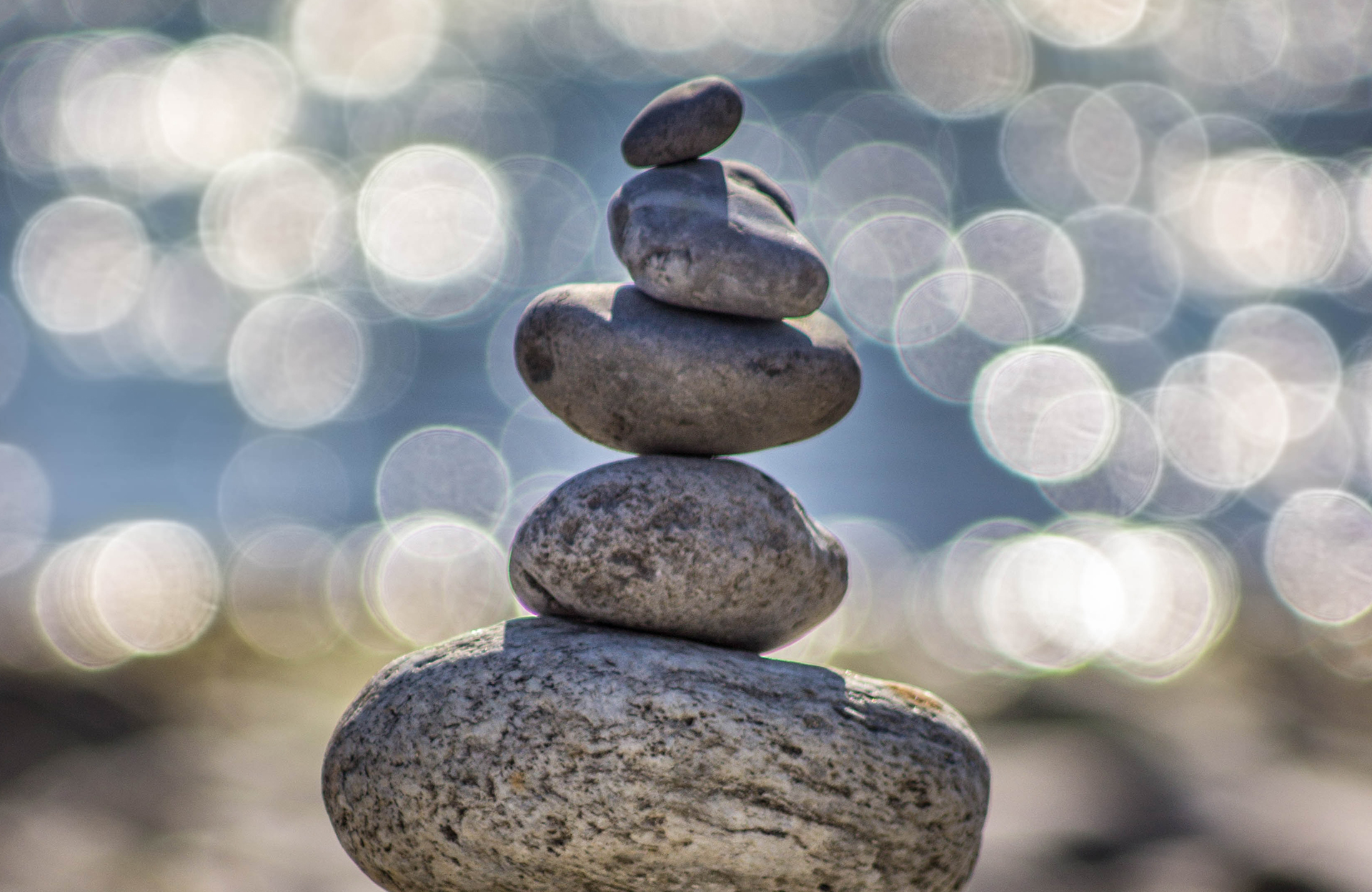 pile of balanced stones with sparkling water in the background